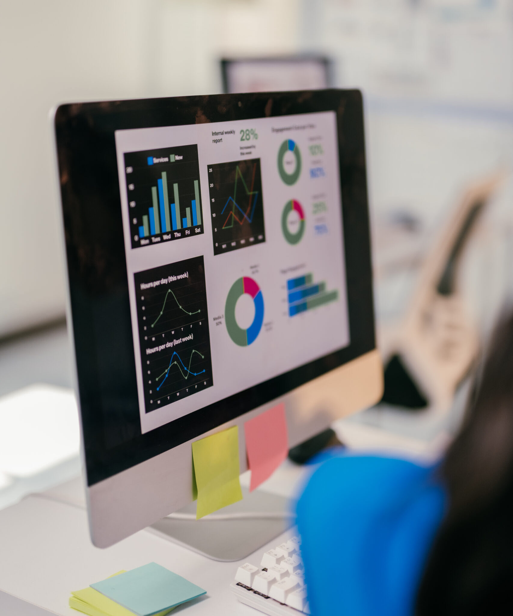 Focused businesswoman analyzes financial data on her computer, using graphs to plan for growth. Her cluttered desk shows her dedication to success